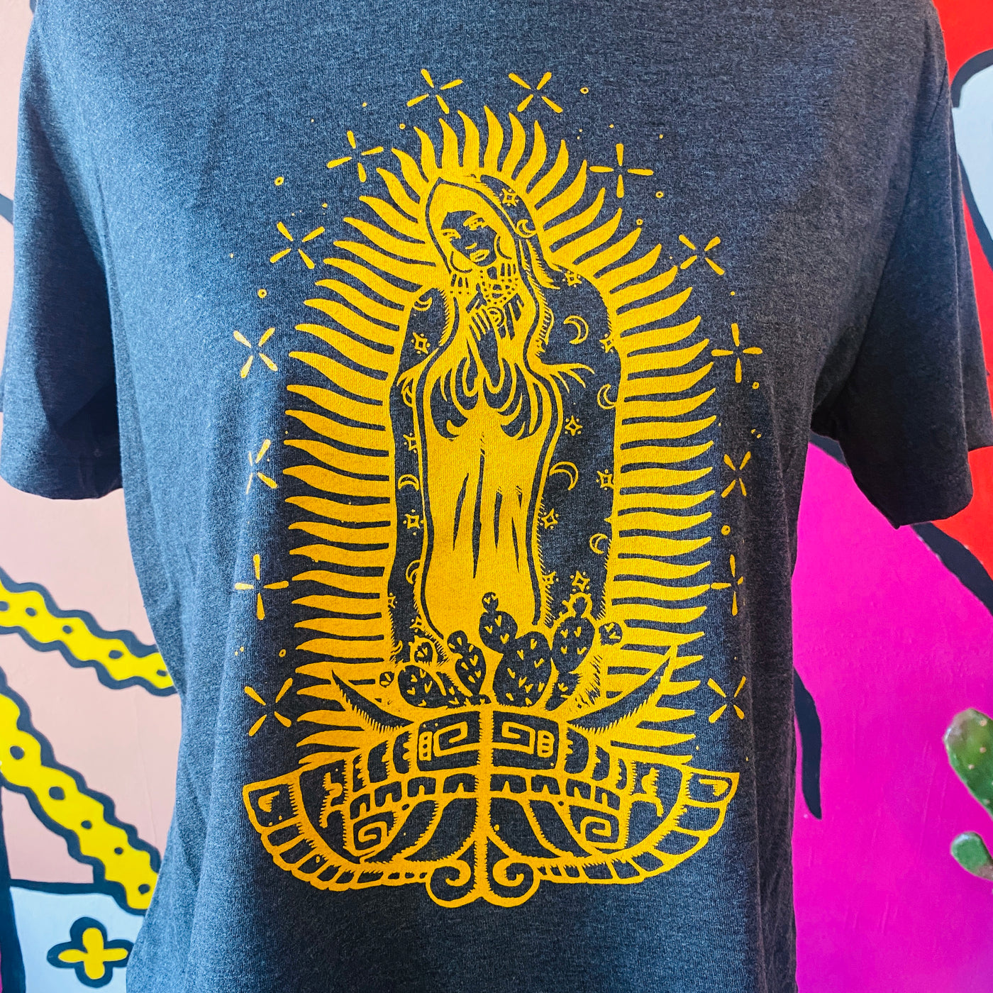 Close up of gray Virgencita t-shirt with yellow detail.