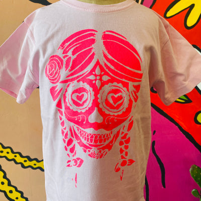 Close up of pink sugar skull with braids kid's shirt.
