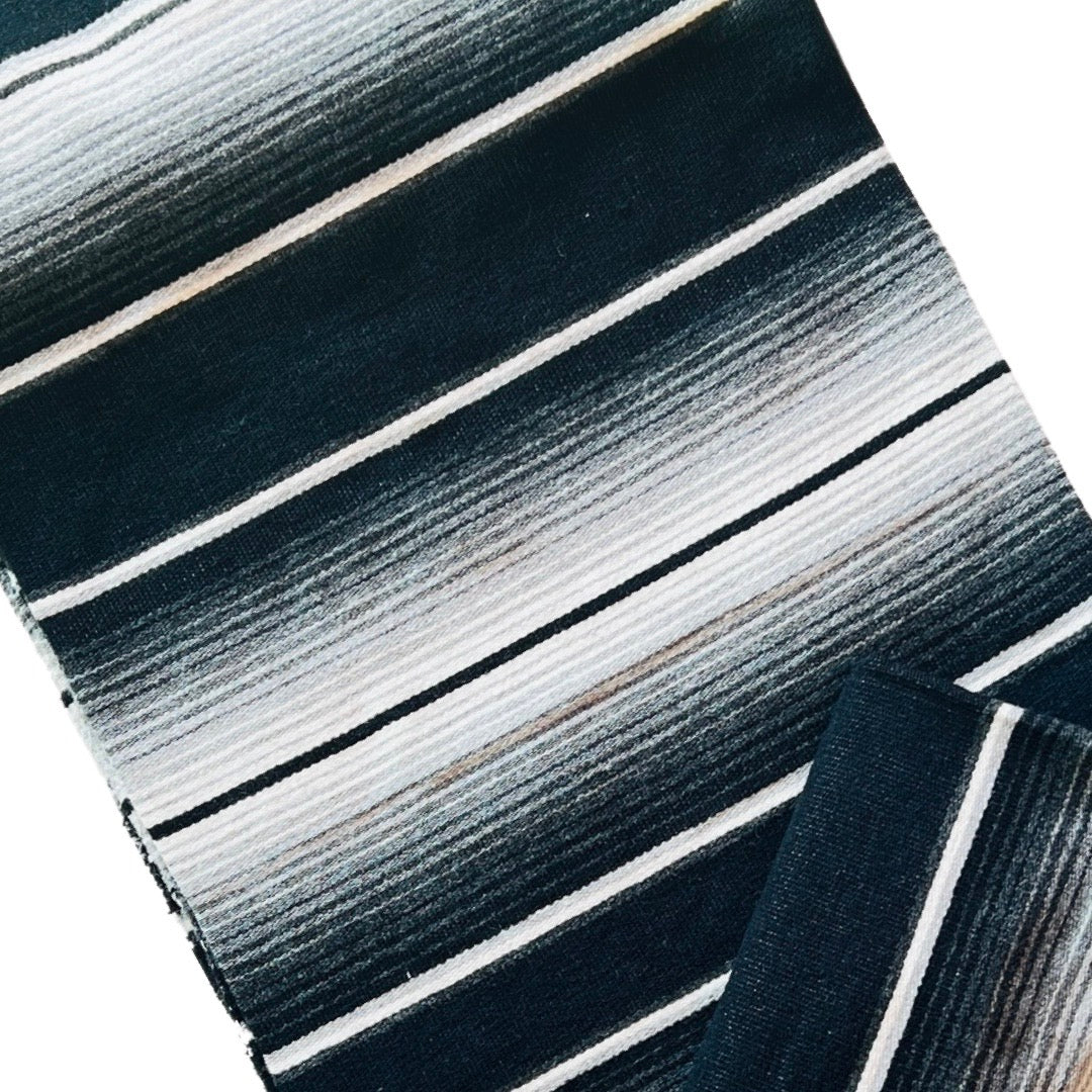 Close up view of a black and white serape striped blanket folded in half.