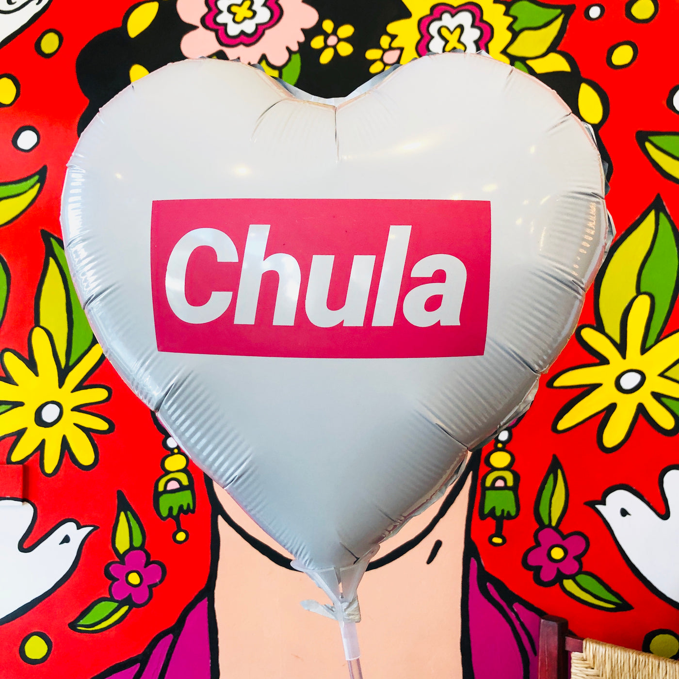 White heart shaped balloon with pink accents that reads, "Chula".