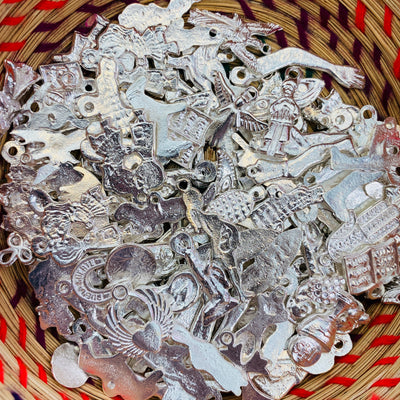 Close up of Milagro (miracle) charms pictured in basket. Silver hardware.