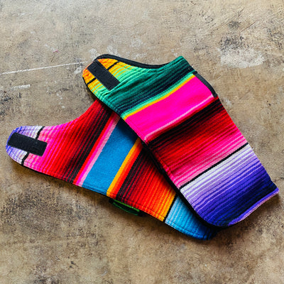 Side view of two colorful ponchos spread across the concrete floor.