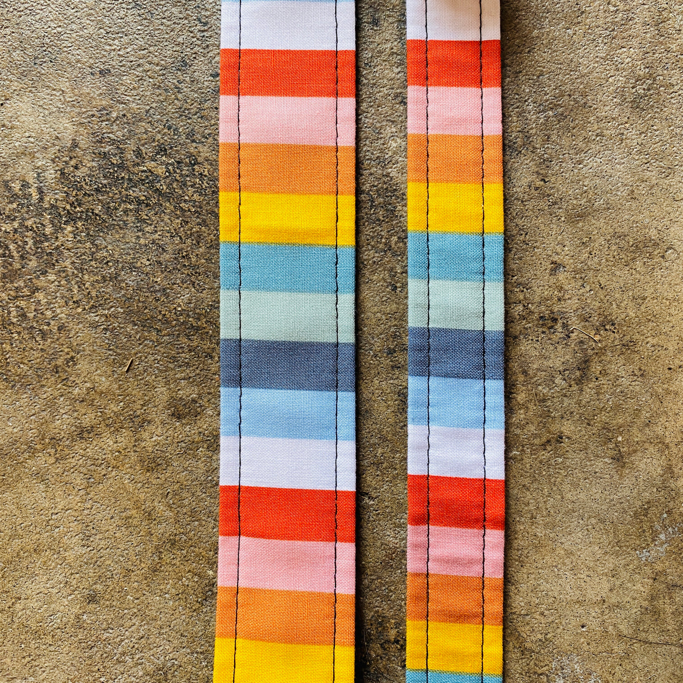 Top view of two different sized colorful striped dog collars. 