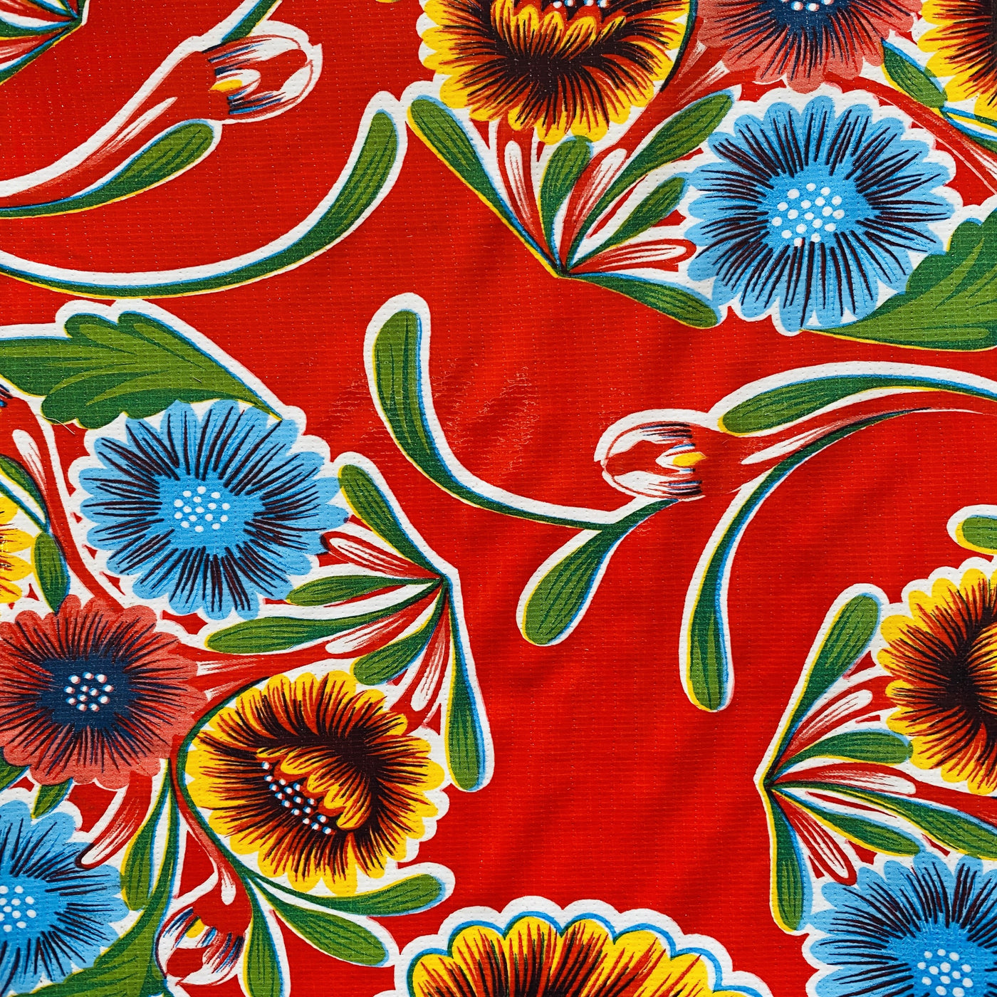 Close up view of red bloom oilcloth table cover showing red, yellow and blue florals.