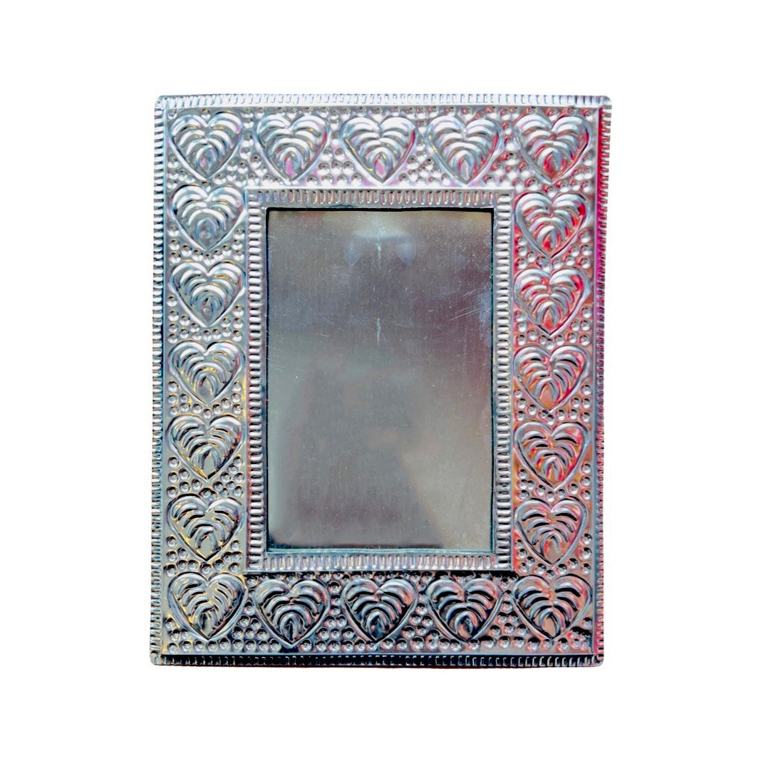 hammered tin frame with a design featuring a monestra leaf and dots.
