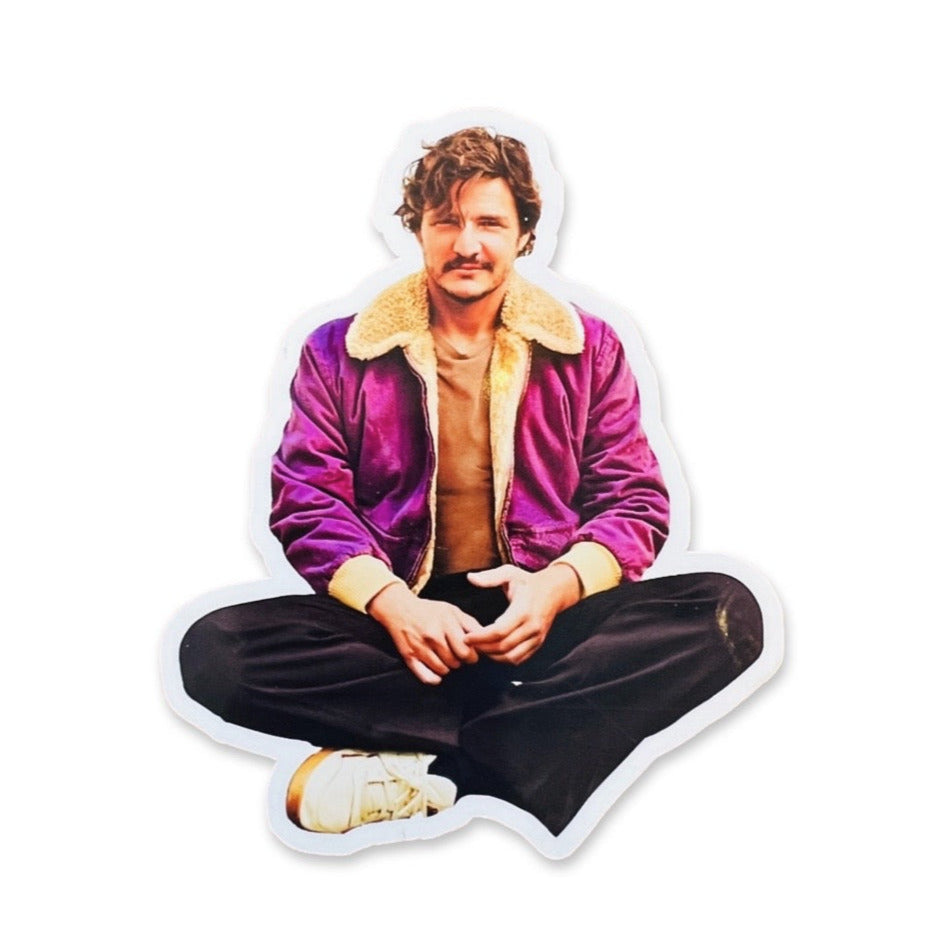 Sticker of Pedro Pascal sitting down crosslegged wearing a purple jacket and black pants.