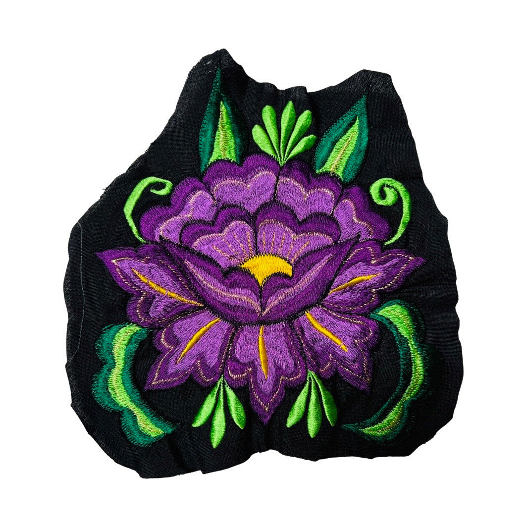 Woven purple flower embroidered on black fabric.