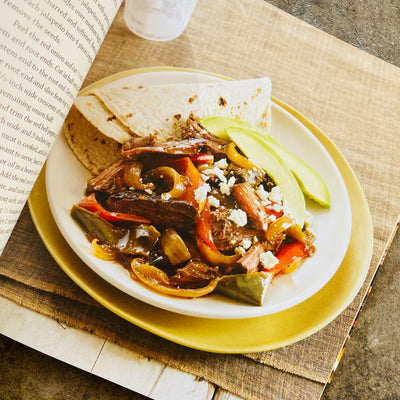 Page inside The Mexican Slow Cooker cookbook. Photo features fajitas with a tortilla on a plate. 