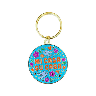 Mi Casa Su Casa enamel circular keychain with gold hardware. Design features teal blue background with flowers and doves. 