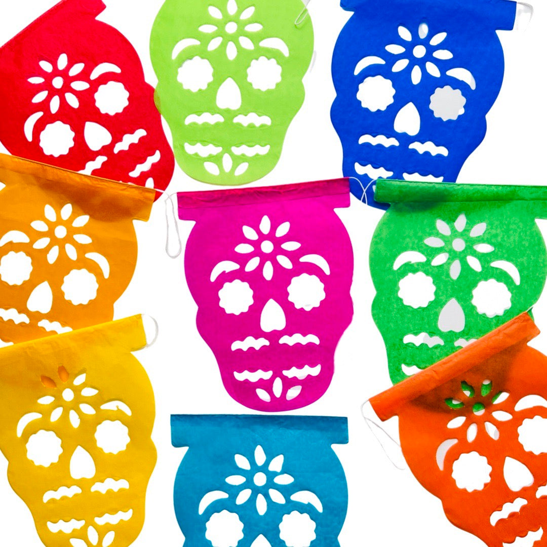 A papel picado banner of various colors and features a sugar skull  design. Papel picado , or perforated paper, is a traditional Mexican decorative craft made by cutting elaborate designs into sheets of tissue paper.