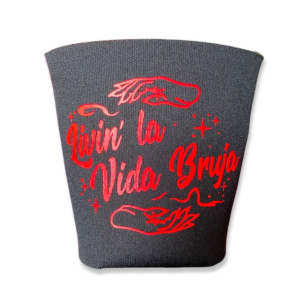 "Living la Vida Bruja" phrase can cooler in black with red lettering. Design features stars and a pair of mystical hands.