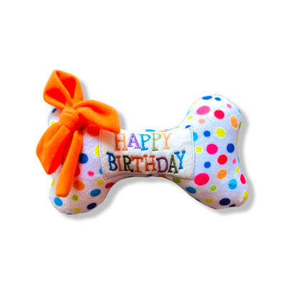Polka dot plush squeaky dog bone toy reading, "Happy Birthday" with orange bow.
