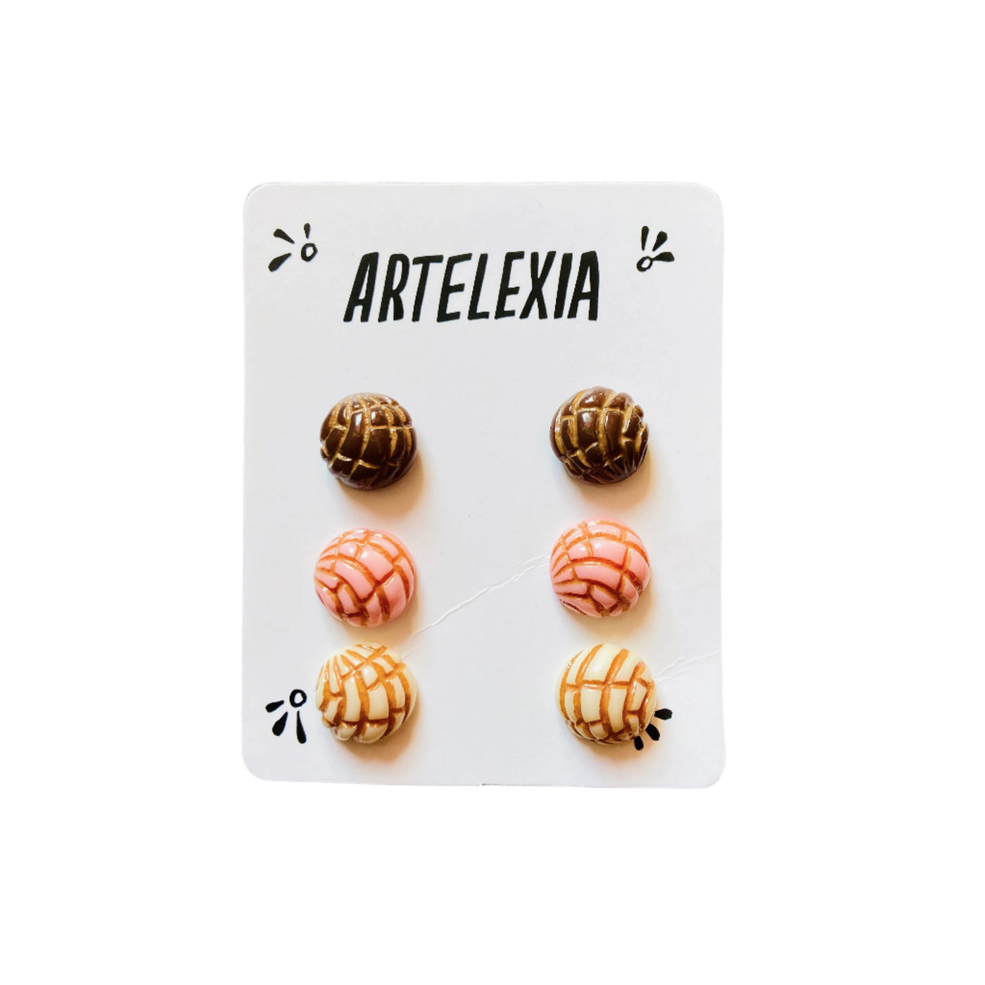 Trio of concha (type of sweet bread) stud earrings in brown, pink, and white with Artelexia branded packaging.  