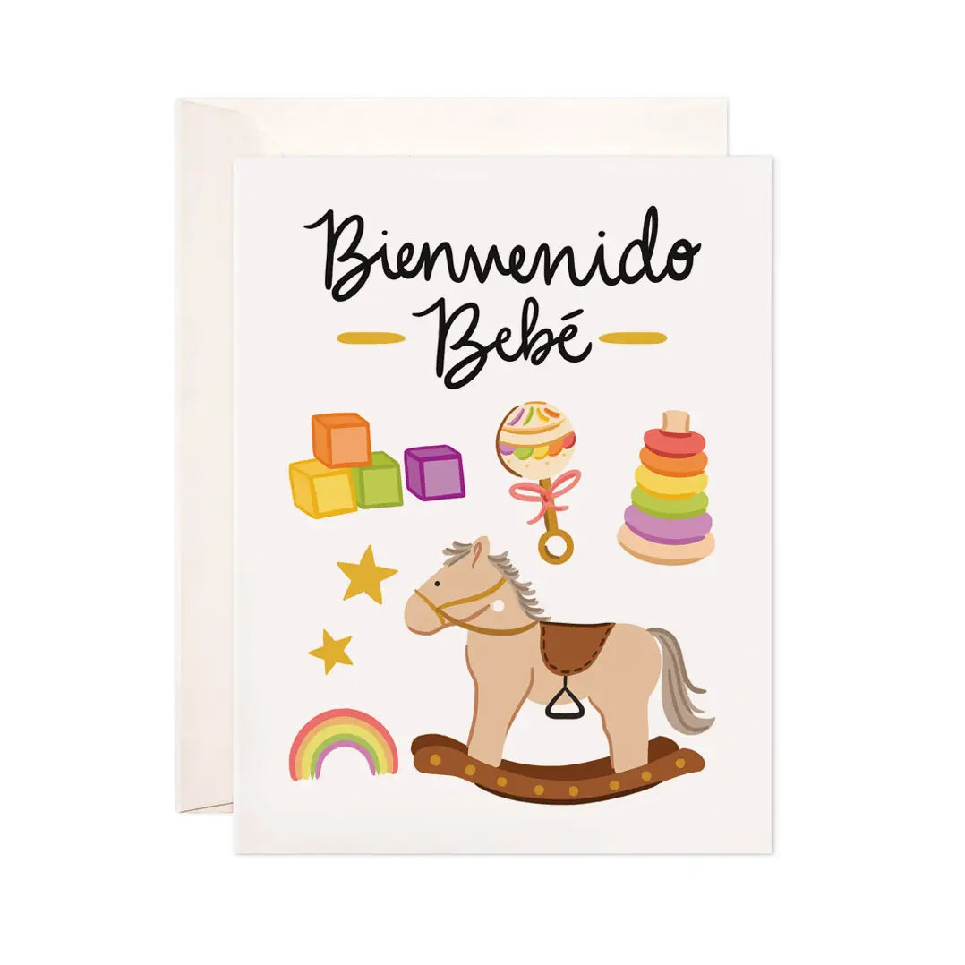Greeting card that features a rocking horse, rattle, raimbow and blocks with the phrase Bienvenido Bebe. Translation: Welcome Baby
