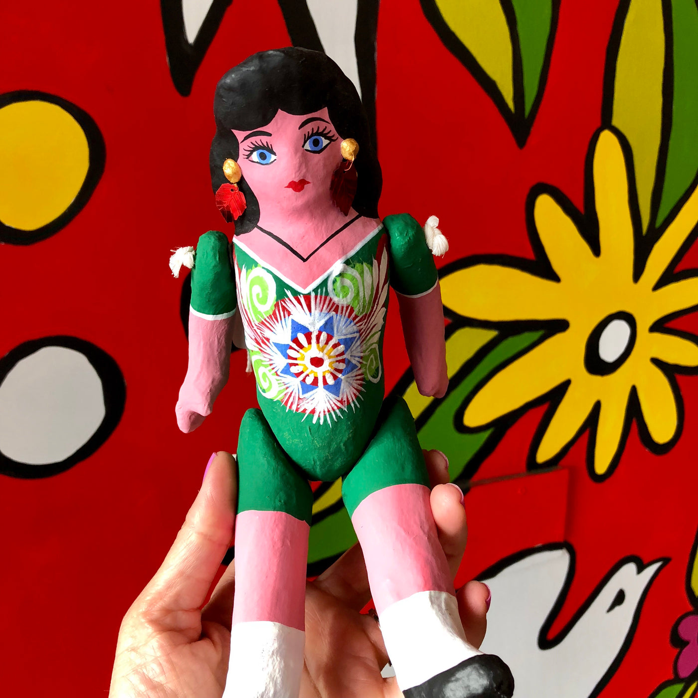 Muñeca de carton doll with moveable arms and legs wearing a green dress.