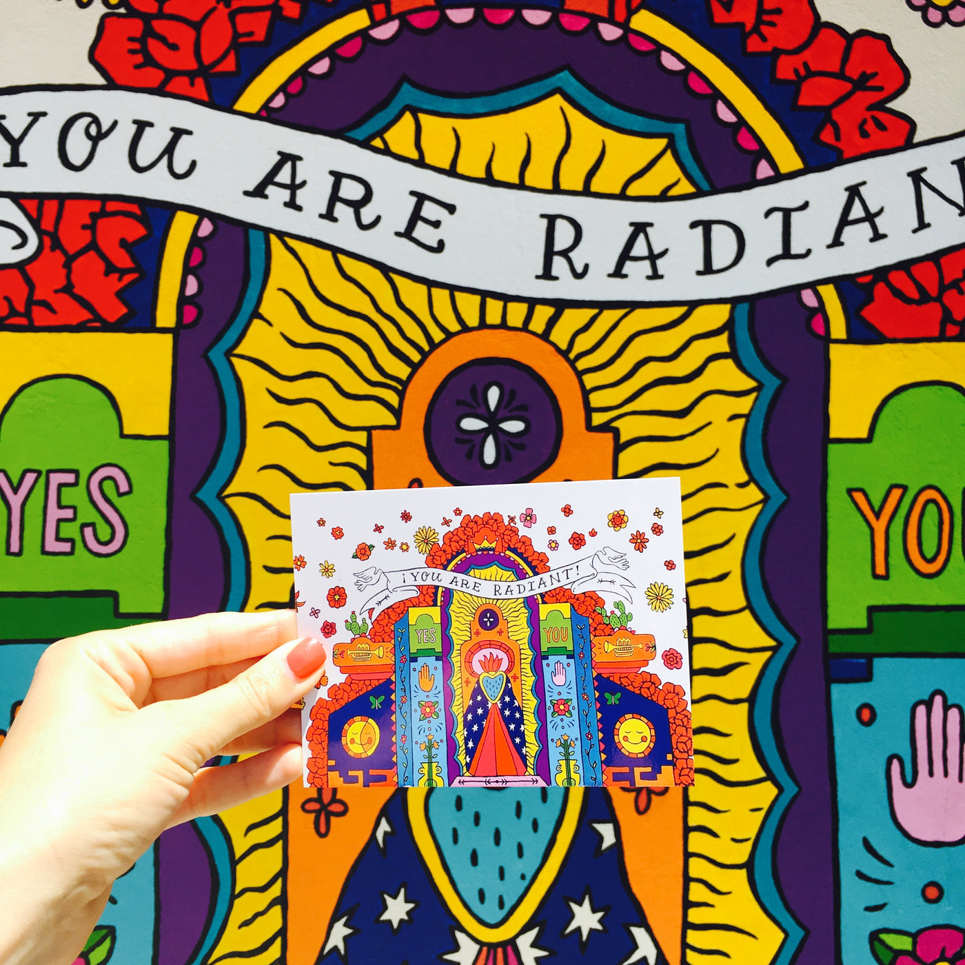 "You Are Radiant!" postcard in front of the real life Artelexia's exterior mural.