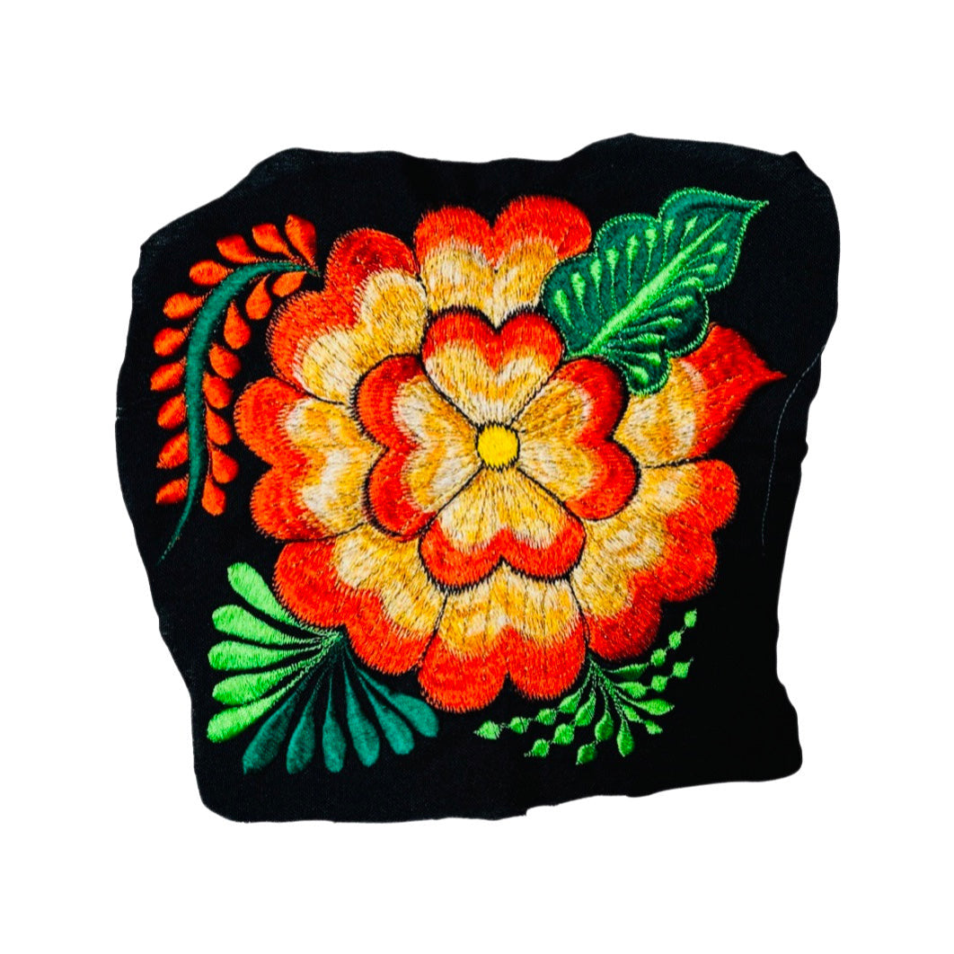 Woven orange flower embroidered on a black fabric.