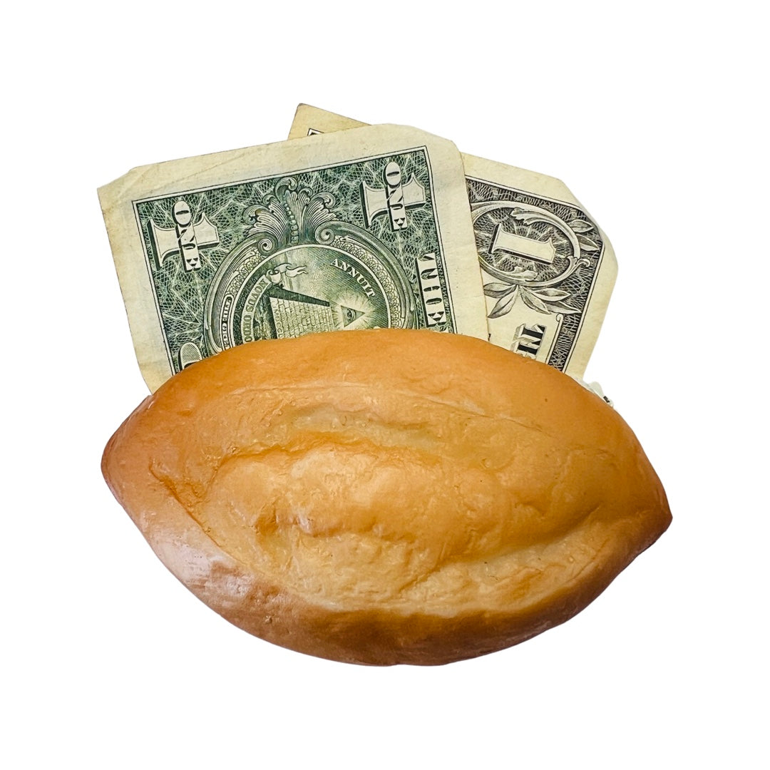 A realistic looking bolillo, Mexican bread, made of rubber with a dollar sticking out of it.