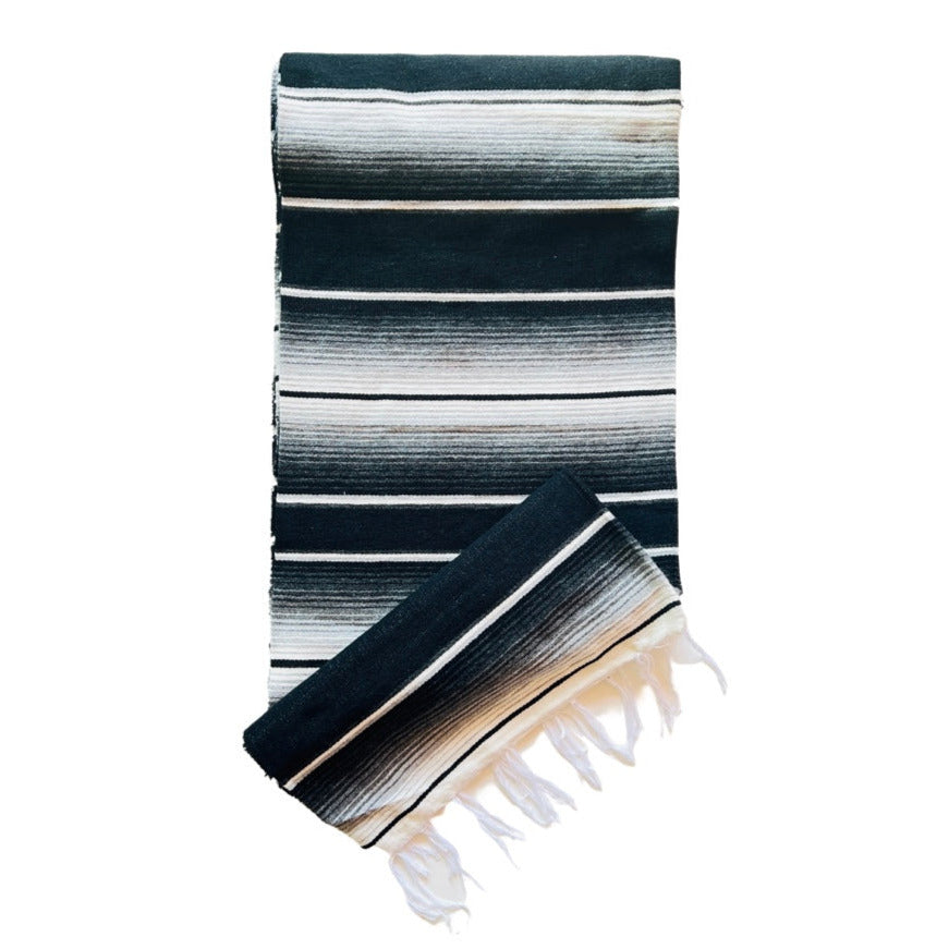 Black and white serape striped blanket folded in half.