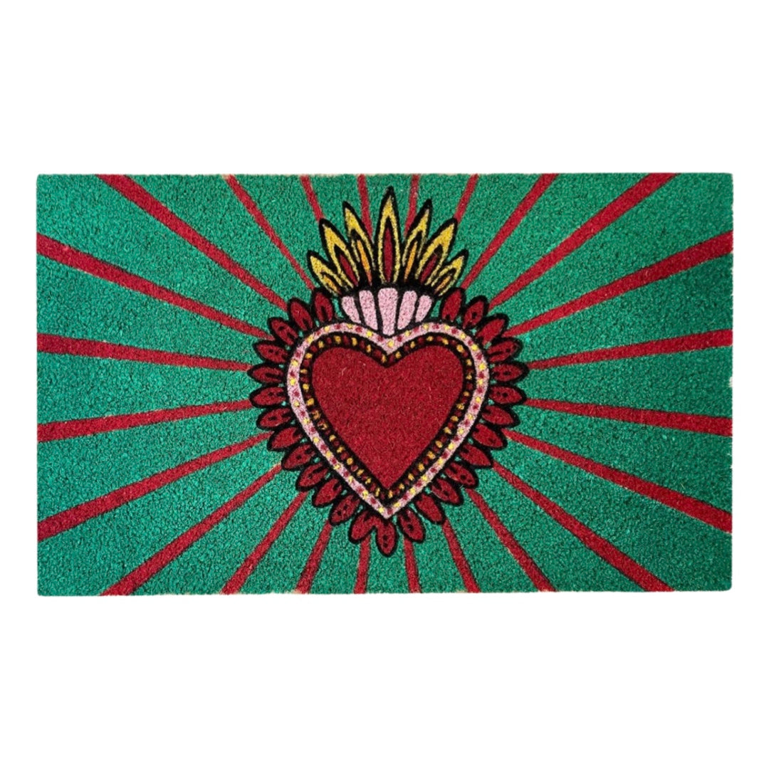 Green and red door mat with a red and pink milagro heart in the center.